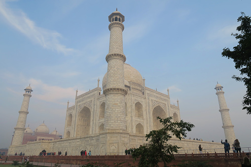 Agra, Uttar Pradesh, India - February 13, 2019: Hazy morning view of the onion dome and minarets of the Taj Mahal seen through archway gate.