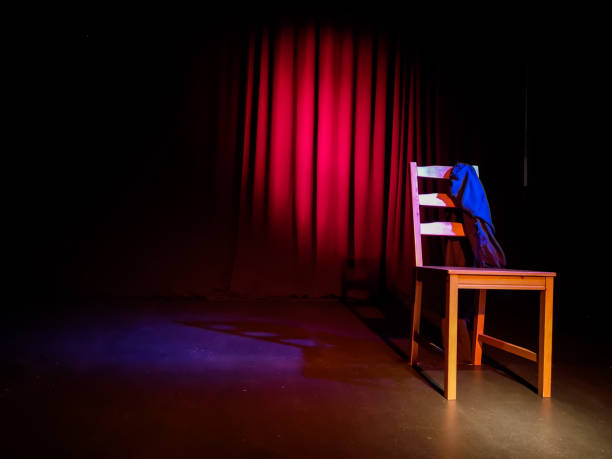 Empty chair on a stage of a theater, concert or comedy show in front of a red curtain Empty chair on a stage of a theater, concert or comedy show lighted by a single spotlight in front of a red curtain audition photos stock pictures, royalty-free photos & images