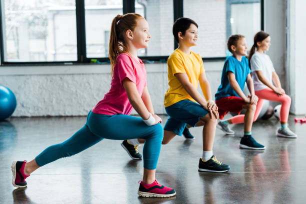 istock Group of cheerful kids doing stretching in gym 1151201982
