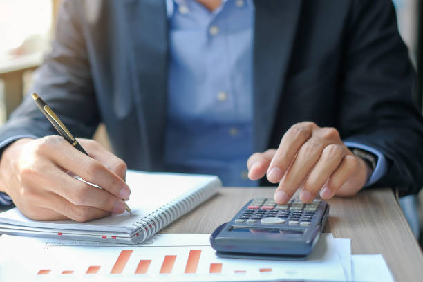 homme d'affaires utilisant la calculatrice pour le plan de maketing d'analyse, gestionnaire calcule le rapport financier et le diagramme graphique.  concepts d'affaires, de finances et de comptabilité - tax graph financial report finance photos et images de collection