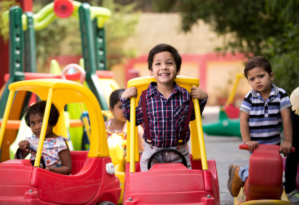 Children having fun playing on toy rides Preschool boys and girls having fun playing on toy car and rocking horse game swing stock pictures, royalty-free photos & images
