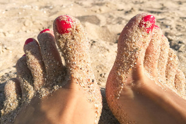 istock Female toes with red pedicure on a sandy beach in summer 1151204096