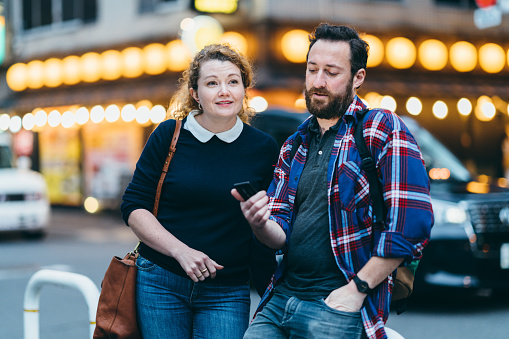 A couple traveler is looking for directions on a smart phone in city.