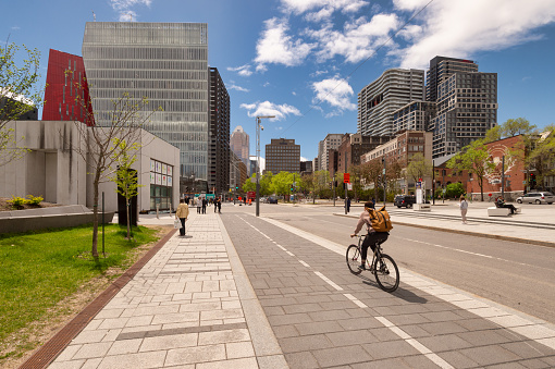 Montreal, Canada - 21 May 2019: A woman is riding a bike on a cycle path, on De Maisonneuve Boulevard.