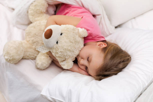 istock Cute little child girl sleeping with teddy bear 1151209200
