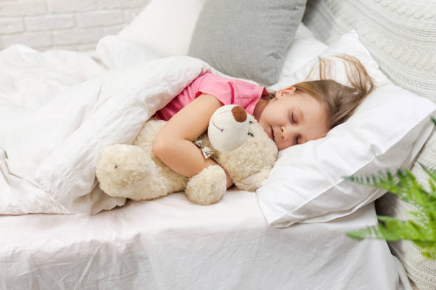 istock Cute little child girl sleeping with teddy bear 1151209201