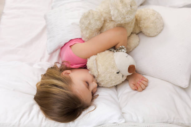 istock Cute little child girl sleeping with teddy bear 1151209203