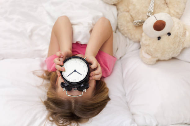 istock Little girl in pyjamas with clock 1151209231