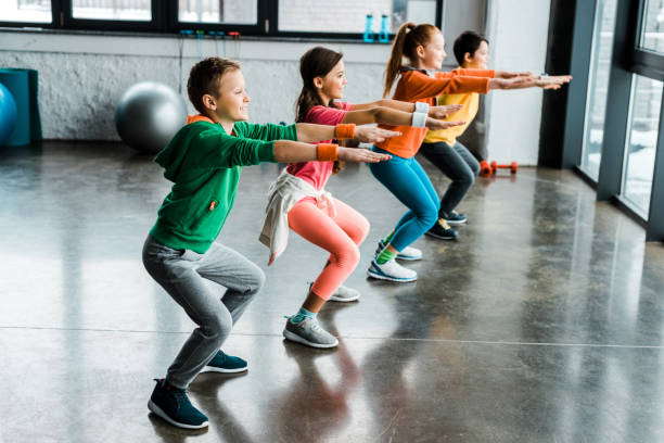 istock Group of kids doing squats in gym 1151211552