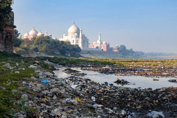 mit müll verschmutzt, der yamuna-fluss mit taj mahal im hintergrund, voll farbig - yamuna river stock-fotos und bilder