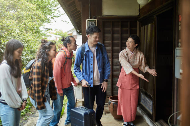 istock Smiling landlady gesturing guests to enter ryokan 1151214864