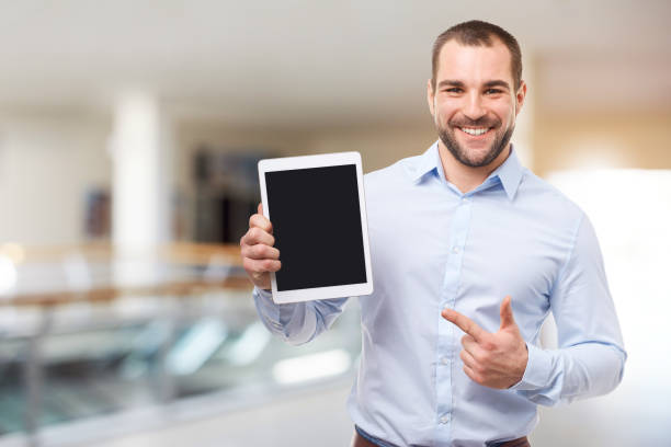 Happy businessman in blue shirt shows touch screen