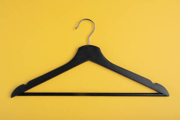 istock Only one black wooden hanger isolated on yellow background. 1151216608