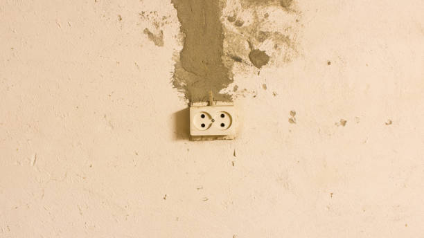 istock Electrical outlet on the old concrete wall. Isolated on light background. 1151218217