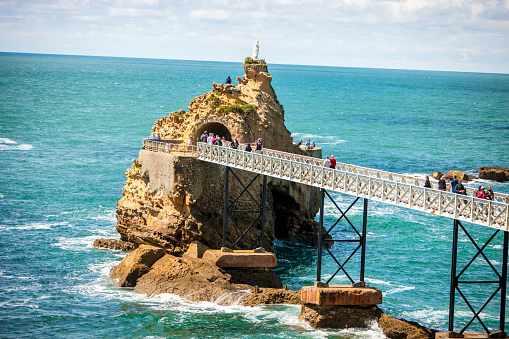 Biarritz, France - May 04, 2019: The Rock of the Virgin Mary, Rocher de la Vierge, Biarritz, France. Tourists on the bridge walking to the famous attraction