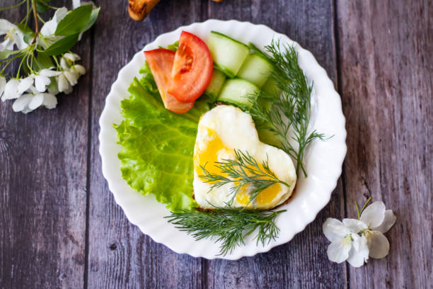 istock Fried eggs with lettuce, cucumber and tomato slices on wooden background 1151221346