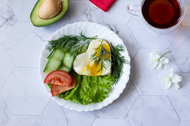istock Fried eggs with lettuce, cucumber and tomato slices on a light background 1151221746