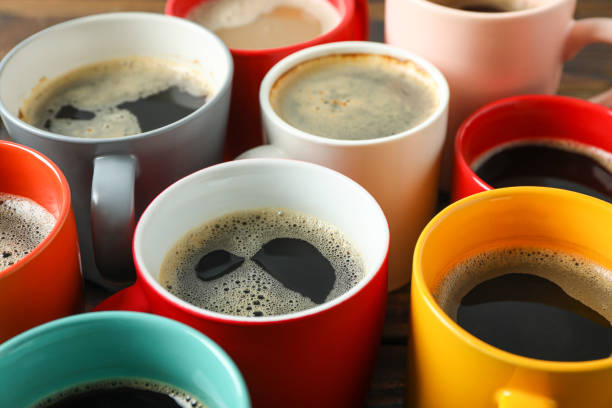 istock Multicolored cups of coffee on wooden table as background, closeup 1151222955