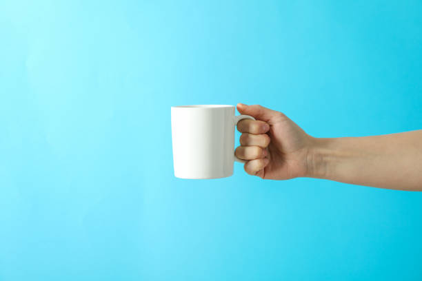 istock Female hand holding white cup against color background, space for text 1151223635