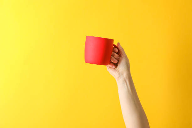 istock Female hand hold red cup against color background, space for text 1151223757