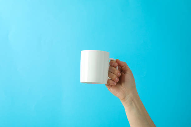 istock Female hand holding white cup against color background, space for text 1151223763