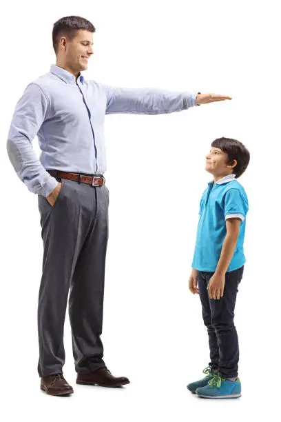 Full length shot of a father measuring how tall his son is isolated on white background