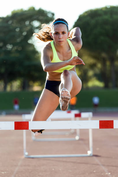 young athlete jumping over a hurdle during training on race track. - hurdling hurdle running track event imagens e fotografias de stock