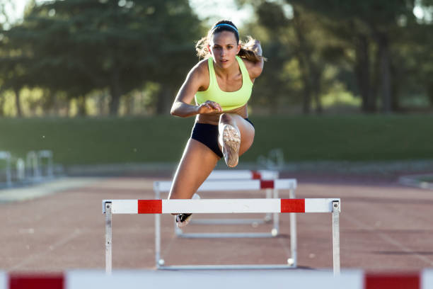 joven atleta saltando sobre un obstáculo durante el entrenamiento en la pista de carreras. - hurdling hurdle running track event fotografías e imágenes de stock