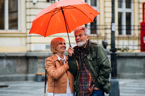 Happy couple standing under red umbrella