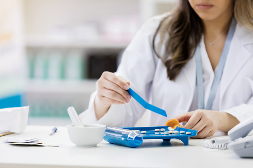 Female pharmacist counts pills and places them in a medication container.