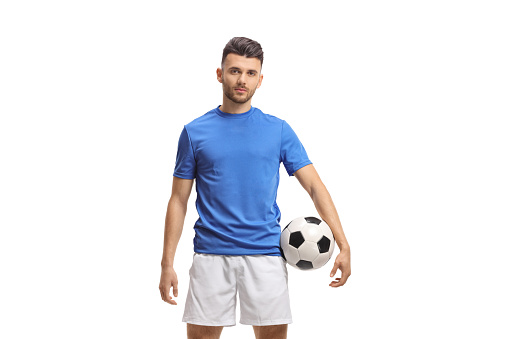 Soccer player holding a football and looking at the camera isolated on white background