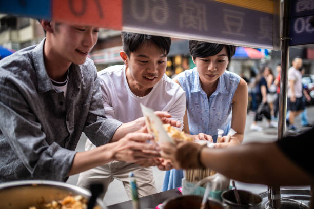 drei personen bestellen an einer straßenfresse essen. - eating men food chopsticks stock-fotos und bilder