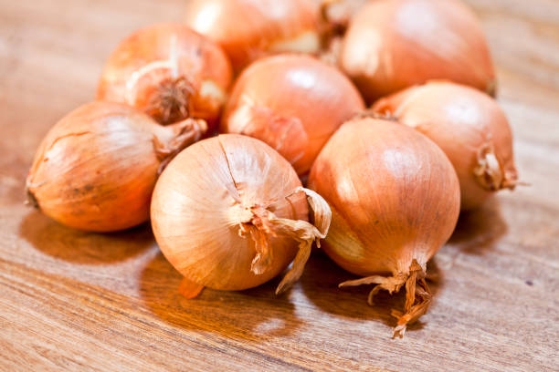 istock Fresh organic onions heap closeup on rustic wooden table. 1151241711