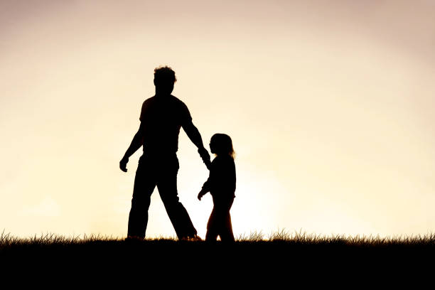 silueta del padre cristiano guiando a su hijo joven de la mano - holding hands child silhouette family fotografías e imágenes de stock