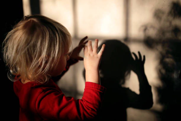 Little Kid Making Shadow Puppets with Fingers on the Wall of her Home stock photo