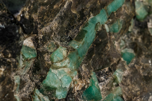 Macro emerald stone mineral in rock on white background close up