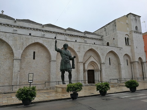 Barletta, Puglia, Italy - May 18, 2019: View of the Basilica of the Holy Sepulcher and of the bronze statue of Heraclius