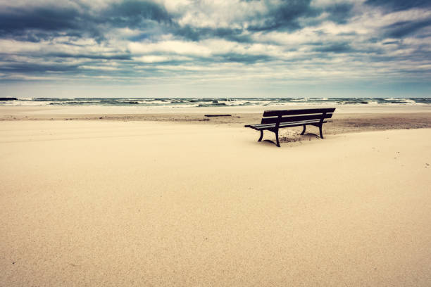 Lonely bench on the beach with view on the sea. Stormy clouds. Unique concepts