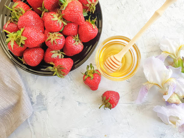 istock fresh strawberries on a plate, honey, iris flower on a gray concrete background 1151264362