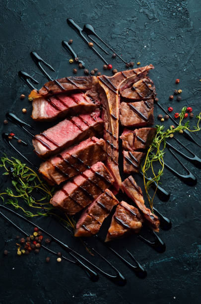istock Beef T-Bone steak on a black table. Top view. Free space for text. 1151267736