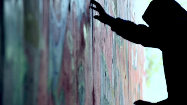 Silhouette of a Man Drawing Graffiti on Wall