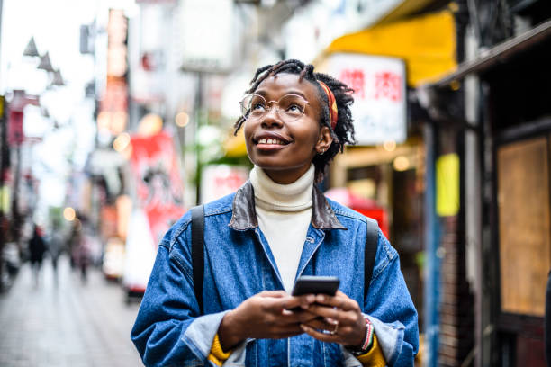 istock Cheerful young woman using smartphone in city 1151279056