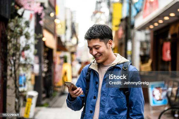 Cheerful Young Man Looking At Smartphone In Street Stock Photo - Download Image Now - Men, Travel, Mobile Phone