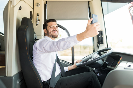 Confident young driver taking selfie while driving tourist bus