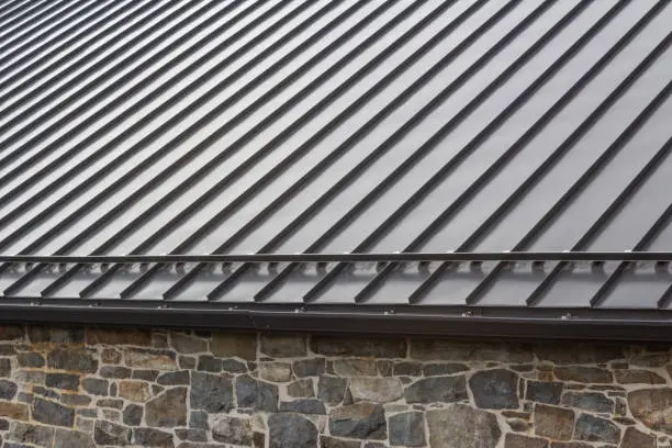 Photo of Standing seam modern metal roof over vintage stone wall