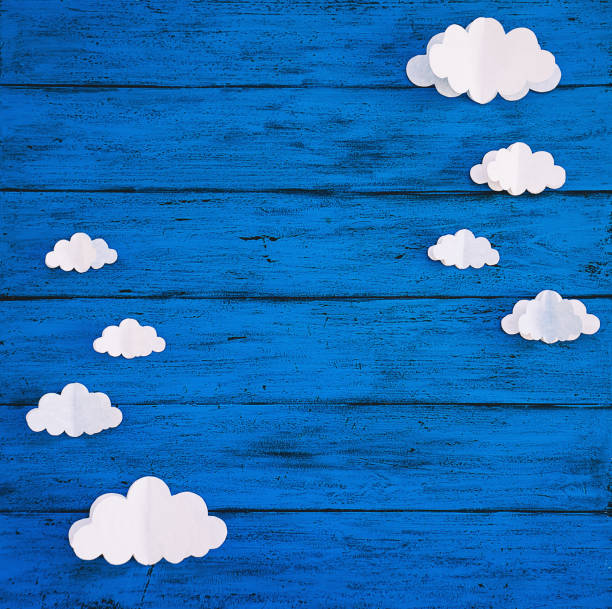 istock Paper handmade crafts clouds on the blue wood background. 1151281331
