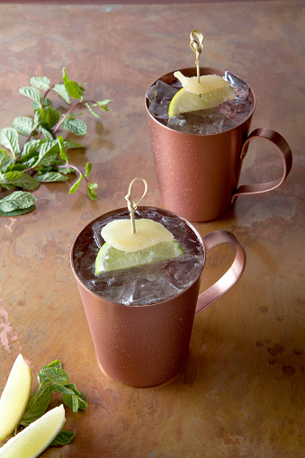 two Moscow mules on a copper bar top with ingredients