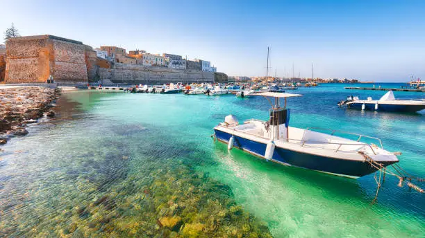 Several fishing boats at the Otranto harbour - coastal town in Puglia with turquoise sea. Italian vacation. Town Otranto, province of Lecce in the Salento peninsula, Puglia, Italy