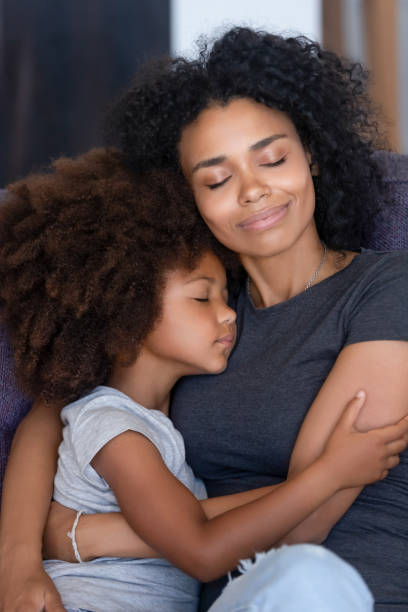 istock Black mom and small daughter hugging tenderly on couch 1151287207