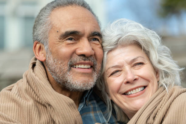 istock Senior couple wrapped in a blanket on a beach 1151287581